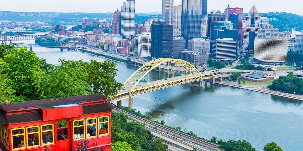 Photo of Pittsburgh's red incline car framing the city's skyline in the distance. 